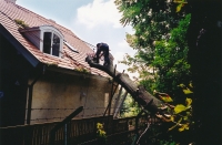 Fällen eines vom Sturm auf ein Hausdach gestürzten Baumes